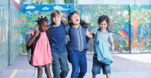 Happy kids embracing and smiling in the elementary schoolyard. Interracial  friendship.