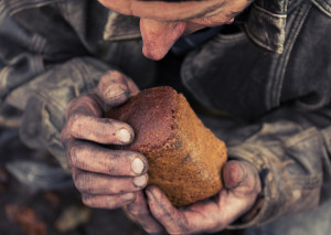 A loaf of bread in an old mans hands