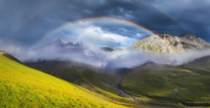 Rainbow in mountain valley during sunset. Beautiful natural landscape