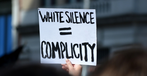 Protest sign stating white silence equals complicity