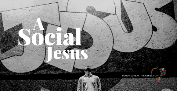 picture of man standing before a wall with "Jesus" graffitied behind him.